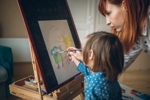 Cute little boy and mother painting and drawing at home. Mother teaching son painting